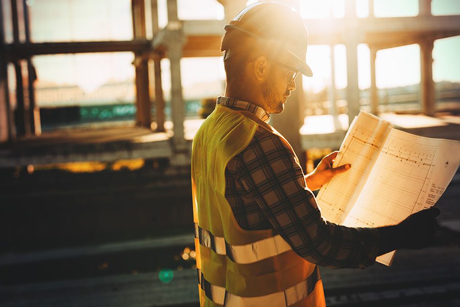 Specialized Business Insurance - Contractor Looking At Building Plans At Construction Jobsite