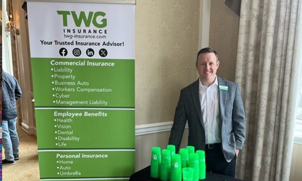 Blog - TWG Insurance Booth with Green Banner and Cups and a Smiling Team Member